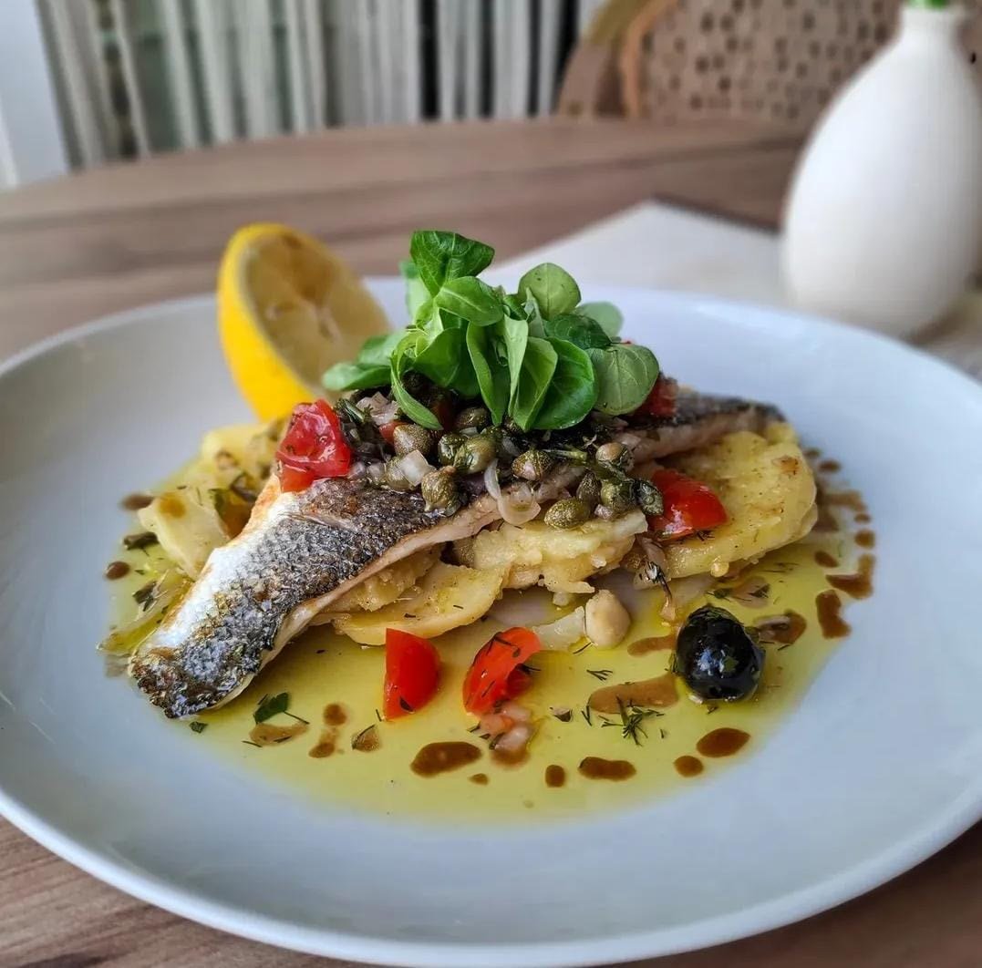 Pan-seared sea bass with crisp skin on sautéed potatoes, with capers, cherry tomato and a vierge sauce