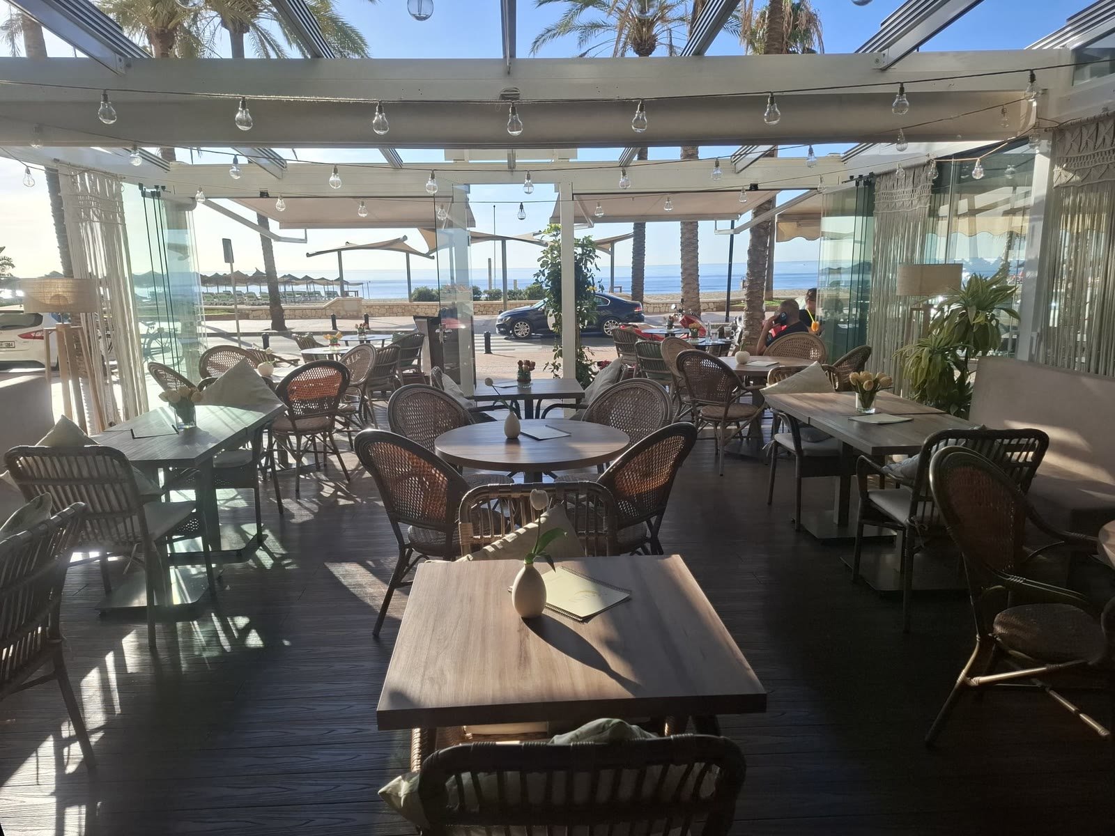 The wide terrace with rattan chairs and palm trees by the sea